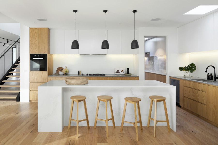 Bếp hoàn thiện với đảo bếp trắng và ghế gỗ